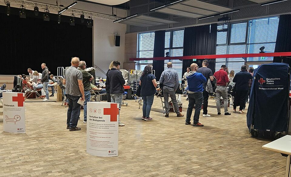 Menschen stehen in einer Schlange und warten auf ihre Blutspende.